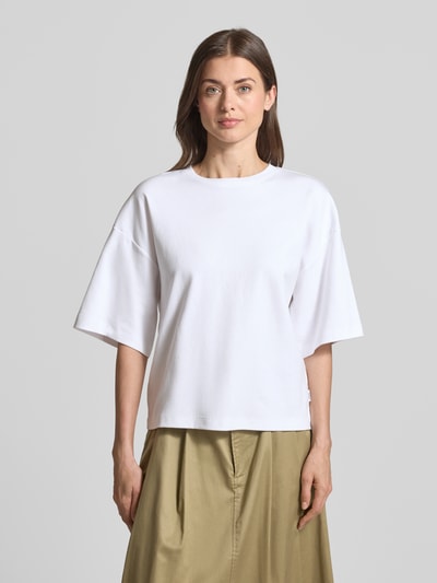 Modelka kobieca nosi Oversized T-Shirt aus reiner Baumwolle von s.Oliver RED LABEL, biała, krój oversized, okrągły dekolt, krótki rękaw, jersey, czysta bawełna, widok całej sylwetki z przodu.