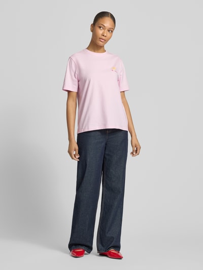 Frauenmodel trägt T-Shirt mit Stitching Modell 'NORA' von Vila in Rosa, Regular Fit, Rundhalsausschnitt, kombiniert mit weiter Jeans und roten Schuhen, Baumwoll-Elasthan-Mix, Ganzkörperansicht von vorne.