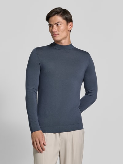 Männermodel trägt schmal geschnittenes, graublaues Slim Fit Longsleeve aus reiner Schurwolle Modell 'Arwon' von DRYKORN, Stehkragen, glatte Textur, Rückenlänge 67 cm, Ärmellänge 68 cm, Ganzkörperansicht von vorne.
