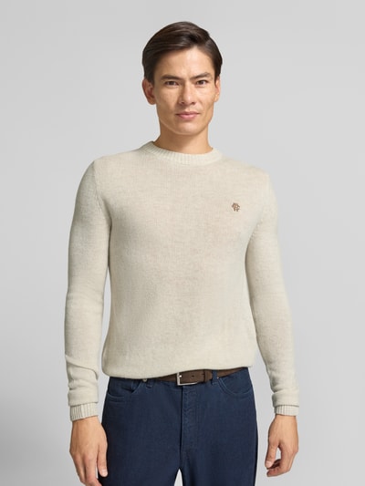 Männermodel trägt Slim Fit Strickpullover aus reiner Wolle mit Label-Stitching von MCNEAL in Beige, gerippte Abschlüsse, Ganzkörperansicht von vorne.