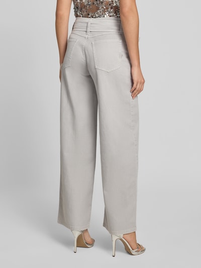 Frauenmodel trägt Wide Fit Jeans mit integriertem Gürtel von BAUM & PFERDGARTEN aus elastischem Baumwoll-Mix, 5-Pocket-Design, hellgrau, Ganzkörperansicht Rückansicht.