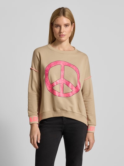Modelka nosi Oversized Sweatshirt mit gerippten Abschlüssen od miss goodlife z bawełny, krój oversized, prążkowane wykończenia, okrągły dekolt, nadruk z motywem, widok całej sylwetki z przodu.