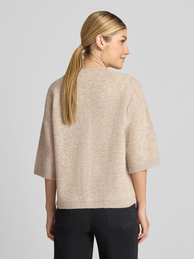 Frauenmodel trägt Strickjacke mit Knopfleiste Modell 'Astrid' von FREE/QUENT, beige, gerippte Struktur, lockere Passform, Ganzkörperansicht Rückansicht.