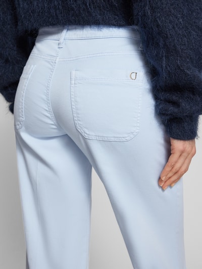 Kobiece model prezentuje Cropped Jeans mit Bügelfalten und Eingrifftaschen von Cambio, jasnoniebieska mieszanka bawełny z dodatkiem streczu, kanty, wpuszczane kieszenie, szerokość w rozmiarze 36: 39 cm, długość wewnętrzna nogawki w rozmiarze 36: 70 cm, ujęcie całej sylwetki z tyłu.