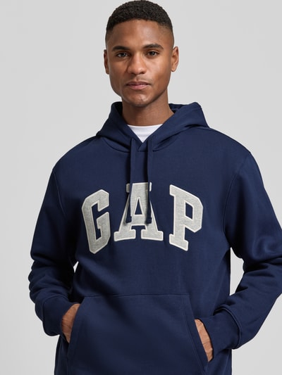 Männermodel trägt Hoodie mit Logo und Känguru-Tasche von GAP in Dunkelblau, Baumwoll-Mix, Regular Fit, Nahaufnahme Oberkörper.