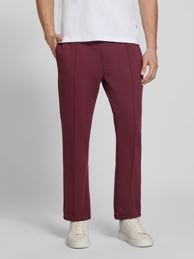Männermodel trägt Straight Fit Hose mit Baumwoll-Anteil Modell 'Parker' von MCNEAL in Dunkelrot, strukturiertes Material, Nahaufnahme Oberkörper, Material-Mix, Gesäßtasche, elastischer Bund, 73 cm Innenbeinlänge bei Größe M.
