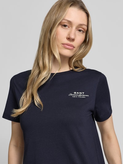 Frauenmodel trägt T-Shirt mit Label-Print und Rundhalsausschnitt von Gant aus Reine Baumwolle, Regular-Fit, dunkelblau, Nahaufnahme Oberkörper. Damen T-Shirt, Rückenlänge bei Größe S: 57 cm.