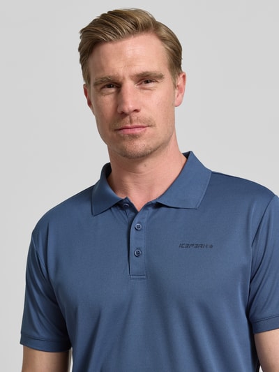 Männermodel trägt Regular Fit Poloshirt mit Logo-Print Modell 'BELLMONT' von Icepeak in Blau, Kurzärmelig, Nahaufnahme Oberkörper.