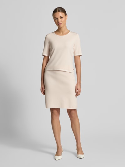 Vrouwenmodel draagt knielange rok uit viscose-mix van Marc Cain, lichte A-lijn, beige kleur, logo-detail, voorkant, volledige lichaamsweergave.