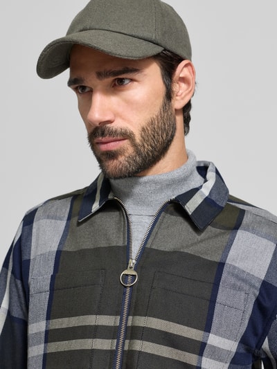 Männermodel trägt Oversized Hemdjacke aus reiner Baumwolle von Barbour, Optik: unifarben, Gitterkaro, Reißverschluss, Label-Detail, Nahaufnahme Oberkörper.