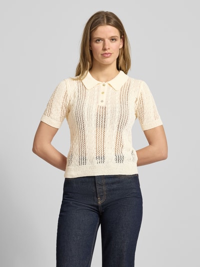 Frauenmodel trägt Slim Fit Poloshirt in Strick-Optik Modell 'Ajour' von Review, cremefarben, Loch-Optik, Ganzkörperansicht von vorne.