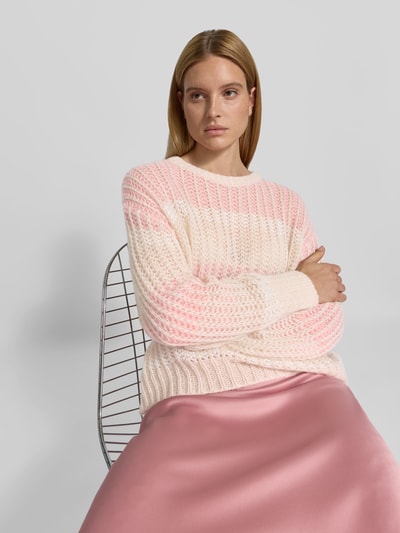Frauenmodel trägt Relaxed Fit Pullover mit Alpaka-Anteil von Juvia, creme-rosa Strick, Lochmuster, Rundhalsausschnitt, Nahaufnahme Oberkörper.