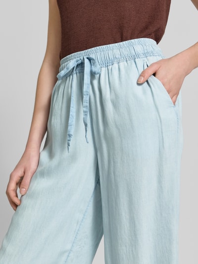 Frauenmodel trägt Wide Fit Stoffhose aus reinem Lyocell in Denim-Optik von Soyaconcept, elastischer Bund, helle blaue Farbe, Nahaufnahme Oberkörper.