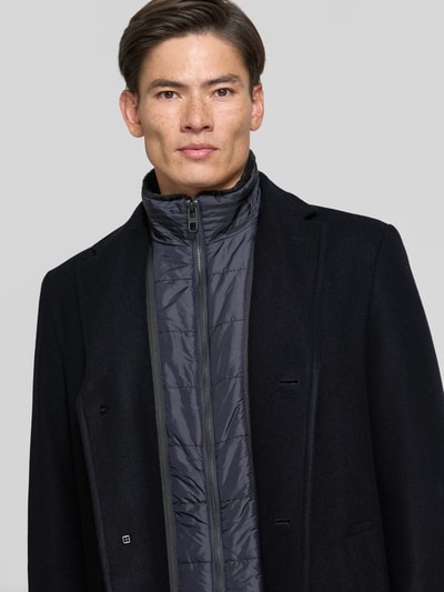 Männermodel trägt Regular Fit Mantel aus Woll-Mix von HECHTER PARIS in Schwarz, Reverskragen, glatte Textur, Nahaufnahme Oberkörper. Rückenlänge 95 cm, Schulterbreite 43 cm, Brustweite 57 cm, Ärmellänge 67 cm.
