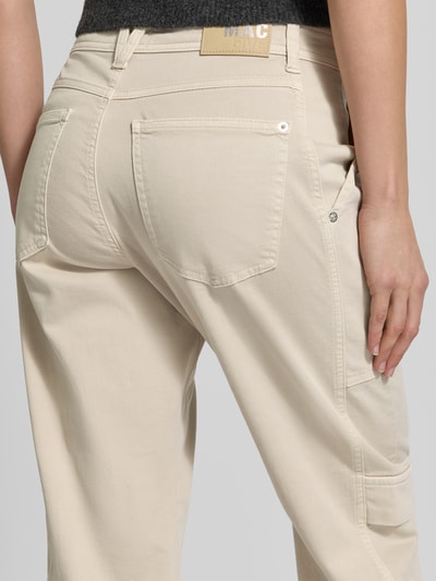 Kobiece modelka nosi spodnie cargo Straight Fit Cargohose aus Baumwoll-Mix Modell 'Ruby 2.0' od MAC, mieszanka bawełny i elastanu, kieszeń wsuwana, kieszeń cargo, kieszeń z tyłu, ozdobne szwy, zapięcie na guzik i zamek błyskawiczny, szerokość w rozmiarze 36: 41 cm, długość wewnętrzna nogawki w rozmiarze 36: 69 cm, beżowy kolor, widoczna tekstura materiału, widok z tyłu, ujęcie detaliczne.