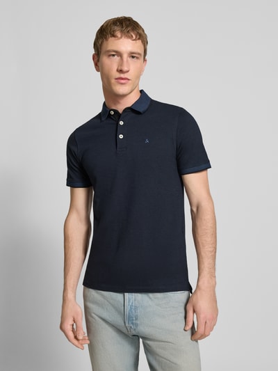 Männermodel trägt Slim Fit Poloshirt mit Viskose-Anteil Modell 'Paulos' von JACK & JONES in Dunkelblau, Baumwoll-Mix, Logo-Stitching, Ganzkörperansicht von vorne.