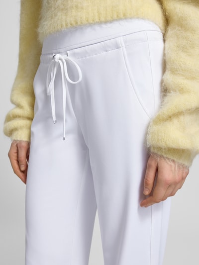 Frauenmodel trägt weiße Straight Leg Jogpants aus Hightech Jersey Modell 'CANDICE' von Raffaello Rossi, elastischer Bund mit Schnürung, Nahaufnahme Oberkörper.