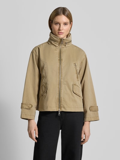 Frauenmodel trägt Jacke mit Stehkragen von Blonde No. 8 in Beige, Reine Baumwolle, Lockerer-Schnitt, Brusttaschen, Eingrifftaschen, Zweiwege-Reißverschluss, Ganzkörperansicht von vorne.