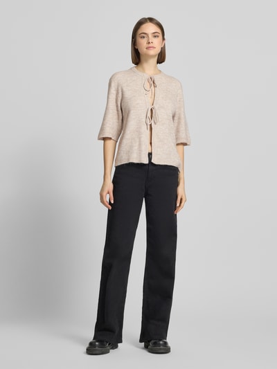 Frauenmodel trägt Regular Fit Cardigan mit Schnürungen Modell 'SIMONI' von Only, beige unifarben, Strickoptik, Ganzkörperansicht von vorne.
