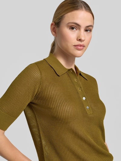 Frauenmodel trägt Lochstrick-Poloshirt - curated by Mary Braun von Style Icon Collection in Braun mit Polokragen, Kurzärmelig, Semitransparent, Strick-Optik, Slim-Fit, Nahaufnahme Oberkörper.