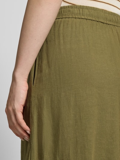 Frauenmodel trägt Midirock aus Leinen-Mix mit Eingrifftaschen von Fynch-Hatton in Khaki, Struktur leicht, Nahaufnahme Oberkörper. Bundweite bei Größe 36: 36 cm, Gesamtlänge bei Größe 36: 87 cm, Leinen-Mix mit Viskose-Anteil, A-Linie, Elastischer Bund mit Kordelzug, Seitliche Eingrifftaschen, Label-Detail.