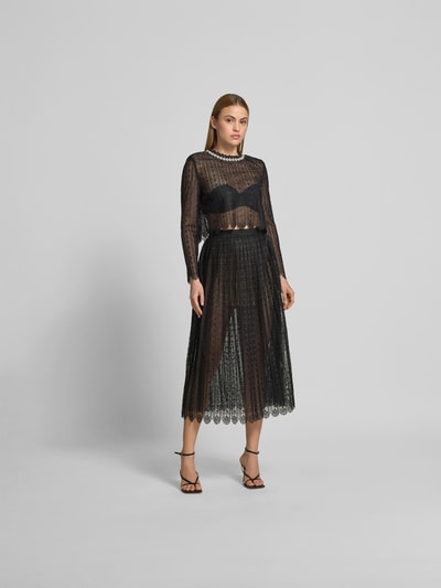 Frauenmodel trägt Slim Fit Longsleeve aus floraler Spitze von Self-Portrait in Schwarz mit Ziersteinbesatz und Schulterpolstern, Ganzkörperansicht von vorne.