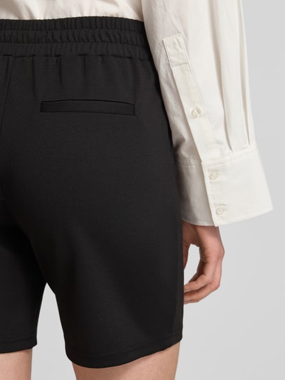 Frauenmodel trägt schwarze Shorts mit elastischem Bund Modell 'Kate' von ICHI aus Material-Mix mit Viskose-Anteil, Detailaufnahme Rückansicht.