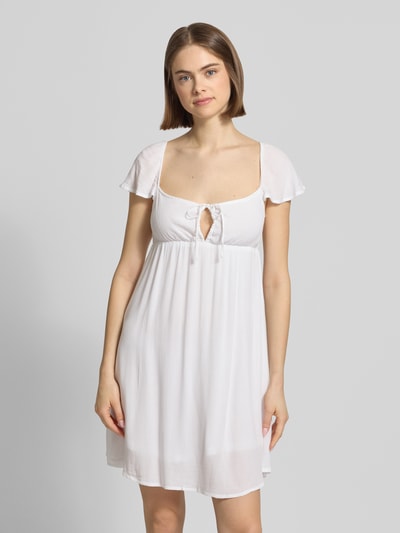 Frauenmodel trägt Babydoll Kleid aus reiner Viskose mit Karree-Ausschnitt und Schleife von REVIEW, gerader Schnitt, Weiß, Minikleid, Ganzkörperansicht von vorne.