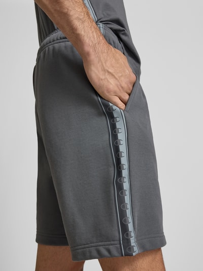 Männermodel trägt Shorts mit Logo und elastischem Bund von CHAMPION im Baumwoll-Mix und Regular Fit in Grau, Nahaufnahme Oberschenkel.