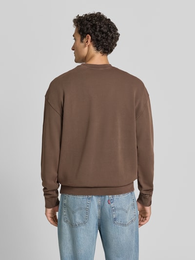 Männermodel trägt Relaxed Fit Sweatshirt aus reiner Baumwolle Modell 'ICONIC Å' von ARMEDANGELS in Braun, glatte Textur, Ganzkörperansicht Rückansicht. Herren Sweatshirt von ARMEDANGELS.
