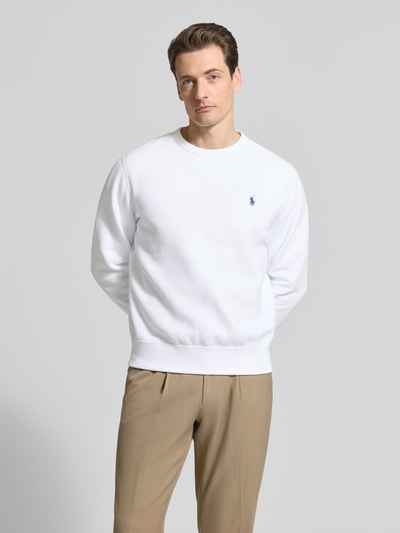 Männermodel trägt Regular Fit Sweatshirt aus Baumwoll-Mix von Polo Ralph Lauren in effen wit met logo-detail, lange mouwen en geribde boorden, ganzkörperansicht von vorne.