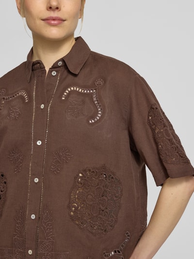 Modelka kobieca nosi Bluse aus Leinen-Baumwoll-Mix mit Motiv-Stitching od Jake*s Casual, brązowy materiał, haft, koronkowe wzory, prosty krój, kołnierzyk koszulowy, listwa guzikowa, rękaw 3/4, długość tyłu 57 cm, długość rękawa 27 cm, widok z przodu, zbliżenie na górną część ciała.