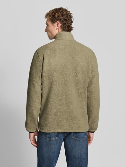Męski model nosi kurtkę z polaru z prostym krojem, stójką, Model 'Jasper' od Columbia, kolor khaki, faktura miękka, długość tyłu w rozmiarze M: 72 cm, długość rękawów w rozmiarze M: 71 cm, szerokość ramion w rozmiarze M: 47 cm, szerokość w rozmiarze M: 46 cm, widok całej sylwetki od tyłu.
