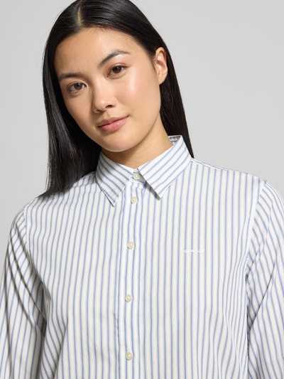 Frauenmodel trägt Regular Fit Bluse mit Label-Stitching von Gant, feine blaue Streifen, reine Baumwolle, Hemdblusenkragen, Nahaufnahme Oberkörper.