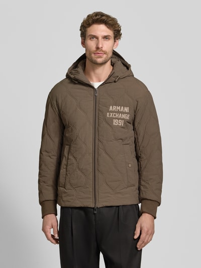 Männermodel trägt Jacke mit Steppnähten und Label-Detail von Armani Exchange in Braun mit Kapuze, Zweiwege-Reißverschluss, Eingrifftaschen, Ganzkörperansicht von vorne.