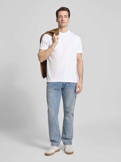 Männermodel trägt T-Shirt mit Rundhalsausschnitt von CK Calvin Klein in Weiß, Regular Fit, Baumwoll-Mix, kombiniert mit Jeans, Ganzkörperansicht von vorne.