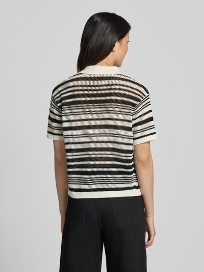 Frauenmodel trägt Regular Fit T-Shirt in Strick-Optik von Comma aus reiner Baumwolle in Schwarz-Weiß mit Polokragen, Rückenlänge 56 cm, Kurzärmelig, Regular-Fit, Ganzkörperansicht Rückansicht.