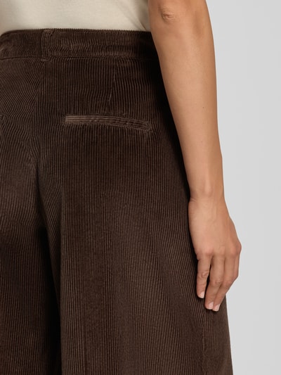 Frauenmodel trägt braune, weit geschnittene Cordhose mit feiner Rippenstruktur, Weite Hose aus reiner Baumwolle Modell 'MELLI S' von Brax, Nahaufnahme Rückansicht, Damen Weite Hose von Brax.