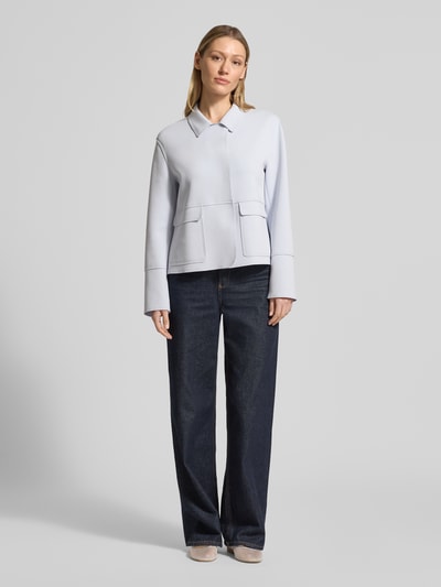 Kobiece model prezentuje żakiet 'Blazer mit Kentkragen und aufgesetzten Pattentaschen' od WHITE LABEL, mieszanka bawełny z dodatkiem streczu, prosty krój, kołnierzyk typu kent, zakryte zapięcie, naszywane kieszenie z patkami, długość tyłu w rozmiarze 36: 57 cm, szerokość w rozmiarze 36: 51 cm, długość rękawów w rozmiarze 36: 61 cm, jasnoniebieski, gładka tekstura, pełen widok z przodu.