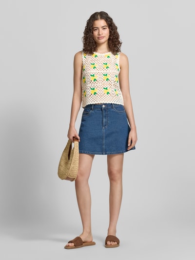 Frauenmodel trägt Boxy Fit Strick-Top mit Allover-Muster Modell 'EMMA' von Only, Struktur-Muster, Rundhals, breite Träger, Materialverarbeitung: Strick, Kombination aus Weiß, Grün und Gelb, Oberteil mit gehäkelter Textur, Ganzkörperansicht von vorne.