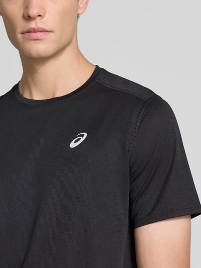 Męski model nosi t-shirt z nadrukiem z logo Model 'CORE' od ASICS TIGER, prosty krój, okrągły dekolt, Długość tyłu w rozmiarze M: 72 cm, zbliżenie na górną część ciała