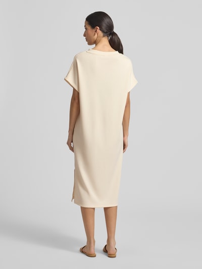 Modelka kobieca ma na sobie T-Shirt-Kleid mit V-Ausschnitt od Soyaconcept, beżowy kolor, prosty krój, materiał z domieszką modalu, długość midi, szerokość w rozmiarze S 59 cm, długość tyłu 110 cm, krótkie rękawy 8 cm; widok całej sylwetki z tyłu.