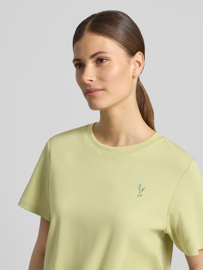 Frauenmodel trägt Regular Fit T-Shirt aus reiner Baumwolle von s.Oliver RED LABEL in Cropped-Länge, Motiv-Print, Label-Applikation, Rundhals, Kurzarm, Jersey, Optik: verkürzt, Farbe: Pastellgelb, Materialverarbeitung: reine Baumwolle, Nahaufnahme Oberkörper.