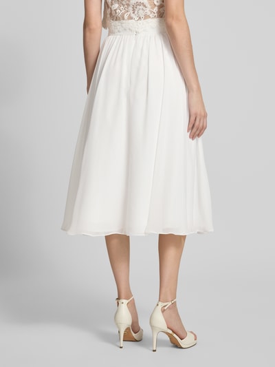 Modelka nosi Midirock aus Chiffon mit Reißverschluss von Luxuar, kremowy, lejący materiał, linia A, szerokość w rozmiarze 36: 38 cm, długość całkowita 77 cm, widok całej sylwetki od tyłu.