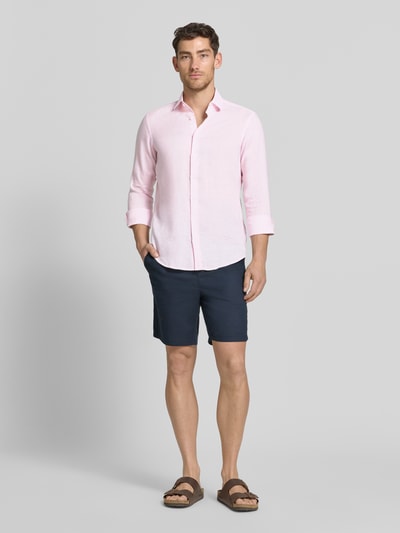 Männermodel trägt Regular Fit Leinenhemd mit Kentkragen von Christian Berg Men in Hellrosa, Struktur glatt, Ganzkörperansicht von vorne.