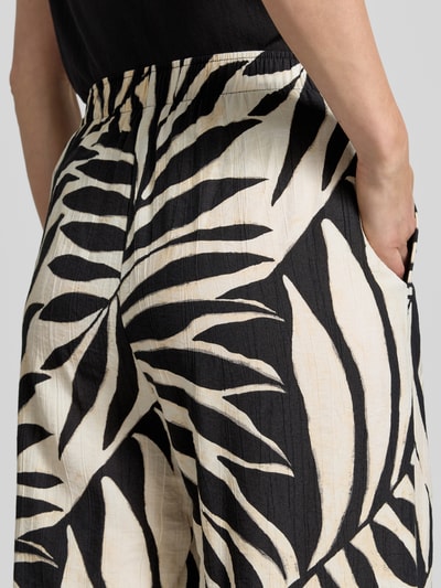 Frauenmodel trägt Wide Fit Stoffhose aus Viskose-Mix Modell 'Life' von Mango mit floraler Allover-Print, Nahaufnahme Hüfte.