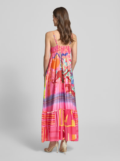 Männermodel trägt Maxikleid aus Viskose Modell 'Sunset Dream' von miss goodlife, A-Linie, Spaghettiträger, Herz-Ausschnitt, długość tyłu w rozmiarze S: 119 cm, szerokość w rozmiarze S: 41 cm, żywe kolory różu, pomarańczu, żółci, całościowy wzór, tekstura lekka, Ganzkörperansicht Rückansicht.