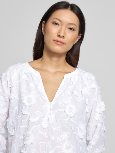 Frauenmodel trägt Regular Fit Bluse mit V-Ausschnitt und 3/4-Arm von Comma, weißer Material-Mix mit floralen Stitchings, Nahaufnahme Oberkörper. Rückenlänge bei Größe 36: 68 cm, Ärmellänge bei Größe 36: 57 cm.