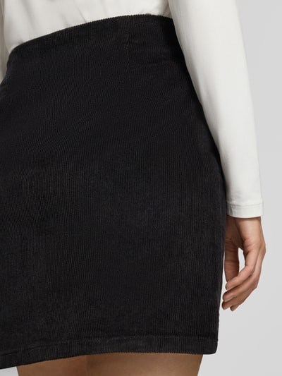 Kobieta modelka nosi czarną spódnicę mini z mieszanki modalu i bawełny Regular Fit Mini-Rock aus Baumwoll-Mix model 'ETTA' od VERO MODA, detaliczne ujęcie z przodu, damska spódnica mini VERO MODA