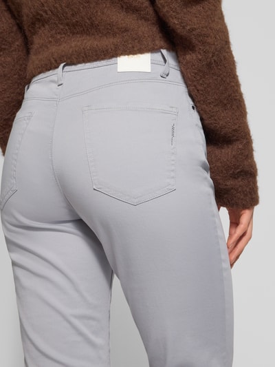Frauenmodel trägt Flared Fit Jeans mit Lyocell-Anteil Modell 'Mary' von Brax in hellem Grau, 5-Pocket-Design, Nahaufnahme Rückansicht.